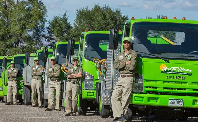 A line of Mesa Turf Masters company trucks and workers standing beside them in Grand Junction, CO.