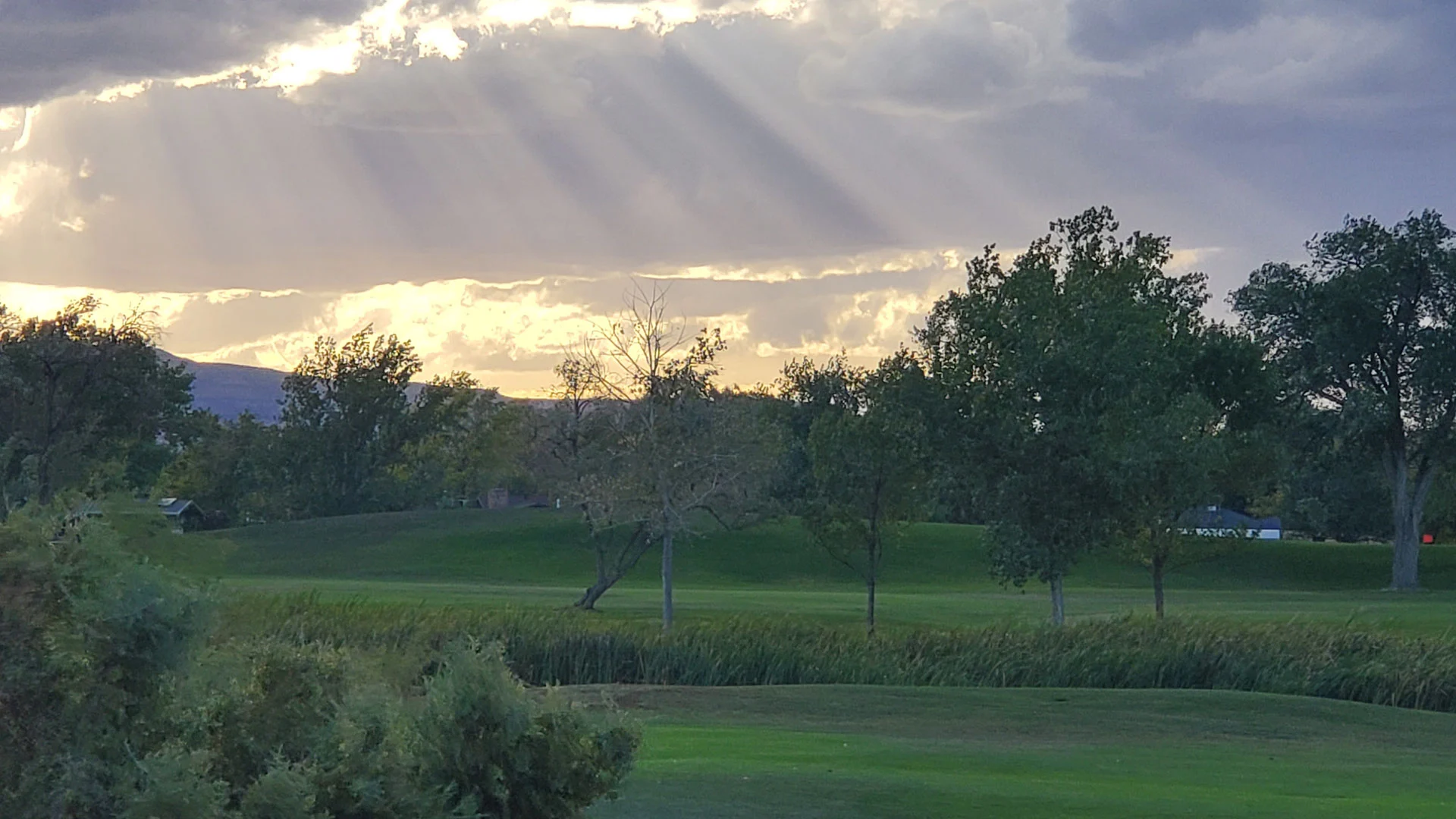 Sunset rays peaking through clouds in the sky over landscape in Redlands, CO.